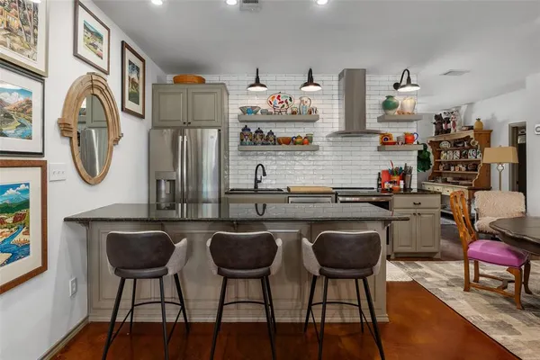 a kitchen with stainless steel appliances granite countertop a stove top oven a dining table and chairs with wooden floor