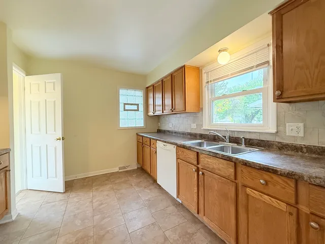 a kitchen with granite countertop a sink window and cabinets