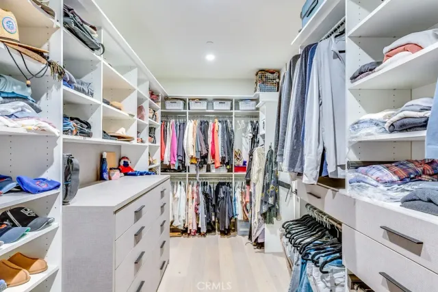 a view of walk in closet with clothes and shoes