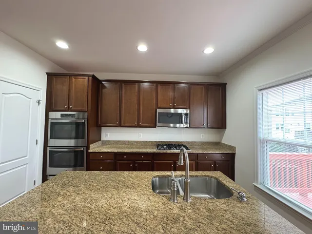 a kitchen with stainless steel appliances wooden cabinets a stove a sink and a refrigerator