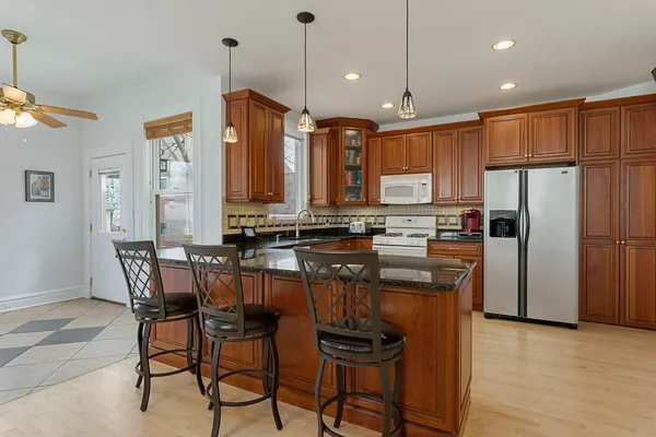 a kitchen with stainless steel appliances granite countertop a refrigerator a stove top oven a sink dishwasher and a dining table with wooden floor