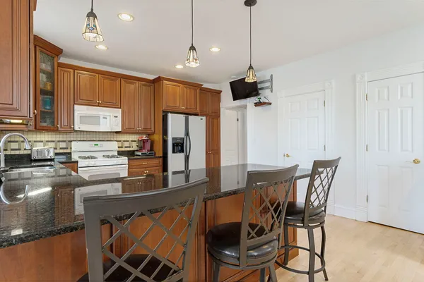 a kitchen with stainless steel appliances granite countertop a stove a refrigerator a kitchen island a table and chairs