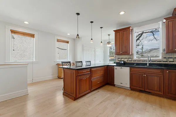 a kitchen with stainless steel appliances granite countertop a sink a stove and a wooden floors