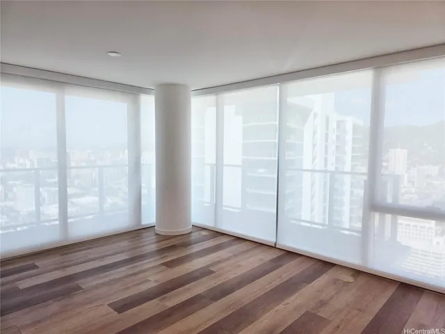 a view of empty room with wooden floor and fan