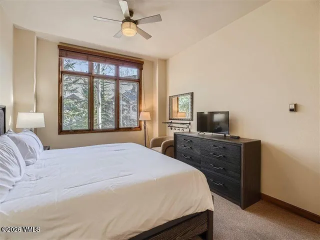 a bedroom with a large bed and a flat tv screen on dresser