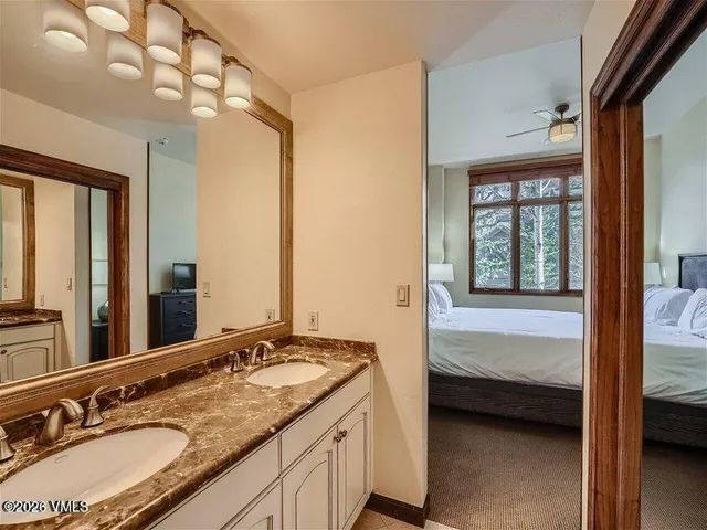 a en suite bathroom with a granite countertop sink and a mirror