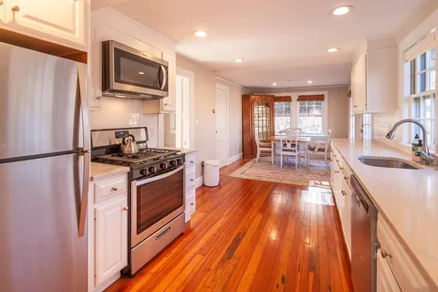 a kitchen with stainless steel appliances granite countertop a refrigerator a stove top oven a sink dishwasher and wooden cabinets with wooden floor