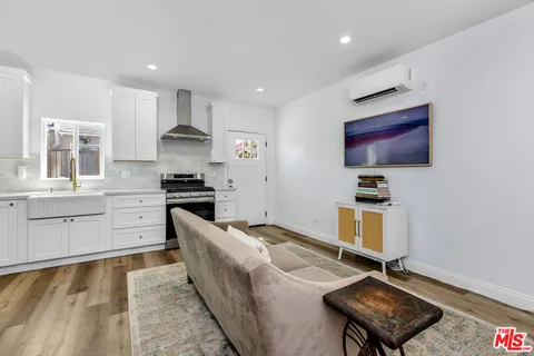 a living room with stainless steel appliances kitchen island granite countertop a stove and a sink