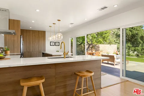 a dining hall with stainless steel appliances granite countertop a sink and a chairs