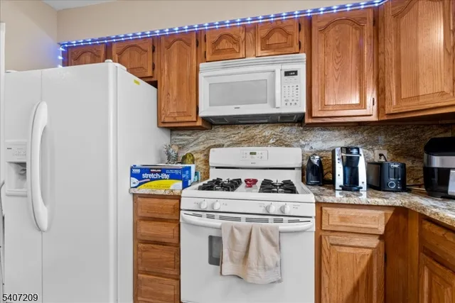 a kitchen with stainless steel appliances granite countertop a refrigerator sink stove and white cabinets