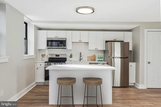 a kitchen with cabinets appliances and wooden floor