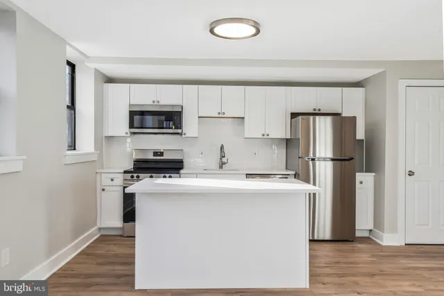 a kitchen with cabinets stainless steel appliances and wooden floor