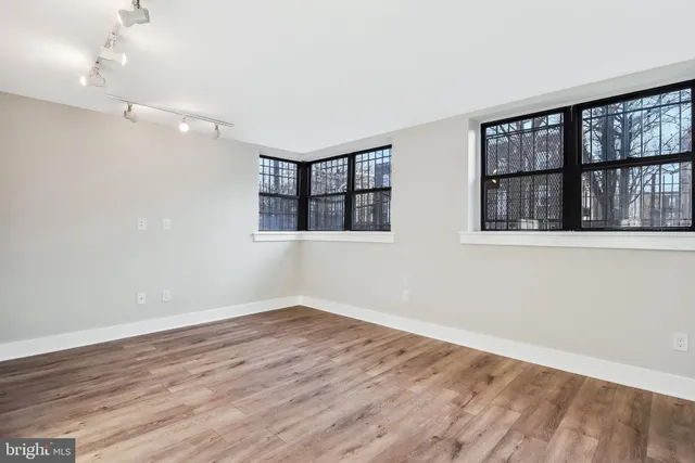 a view of an empty room with wooden floor and a window