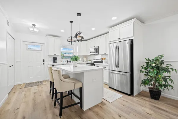 a kitchen with stainless steel appliances a refrigerator a stove a sink and a dining table with wooden floor