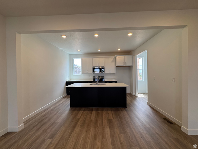 1883 West 1575th North, Unit 236 Layton, UT 84041 - Photo 5 of 22 Kitchen with recessed lighting, a center island with sink, dark wood finished floors, white cabinetry, and light countertops