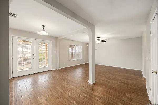 a view of an empty room with wooden floor and a window
