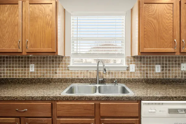 a kitchen with granite countertop a sink a counter space and cabinets