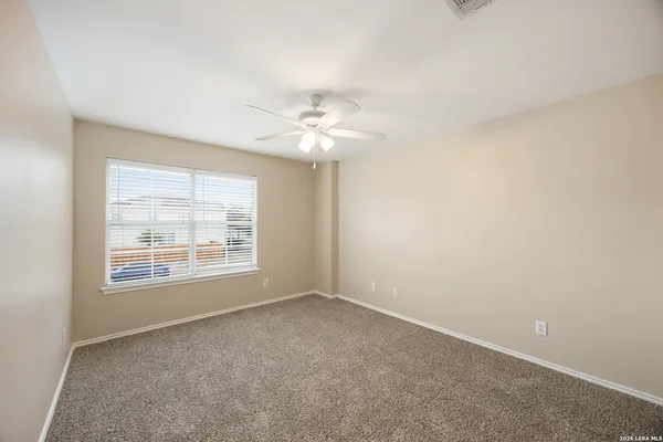 an empty room with a chandelier fan and windows