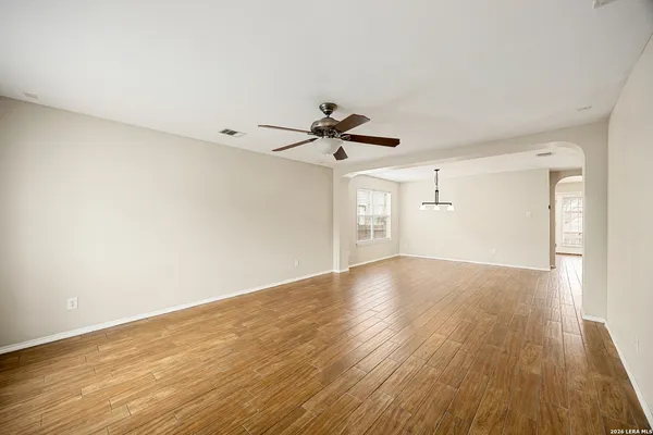 a view of empty room with wooden floor and fan