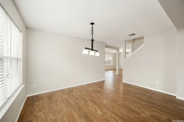a view of a room with wooden floor ceiling fan and windows