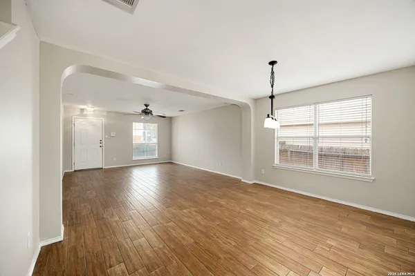 a view of an empty room with wooden floor and a window