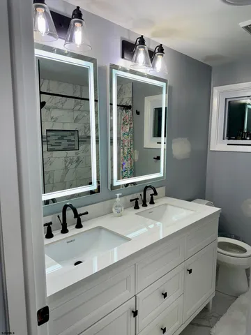 a bathroom with a sink a toilet a mirror and shower