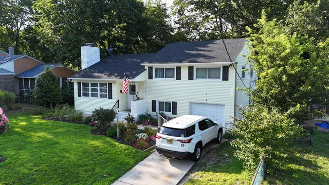 a front view of a house with a garden and trees