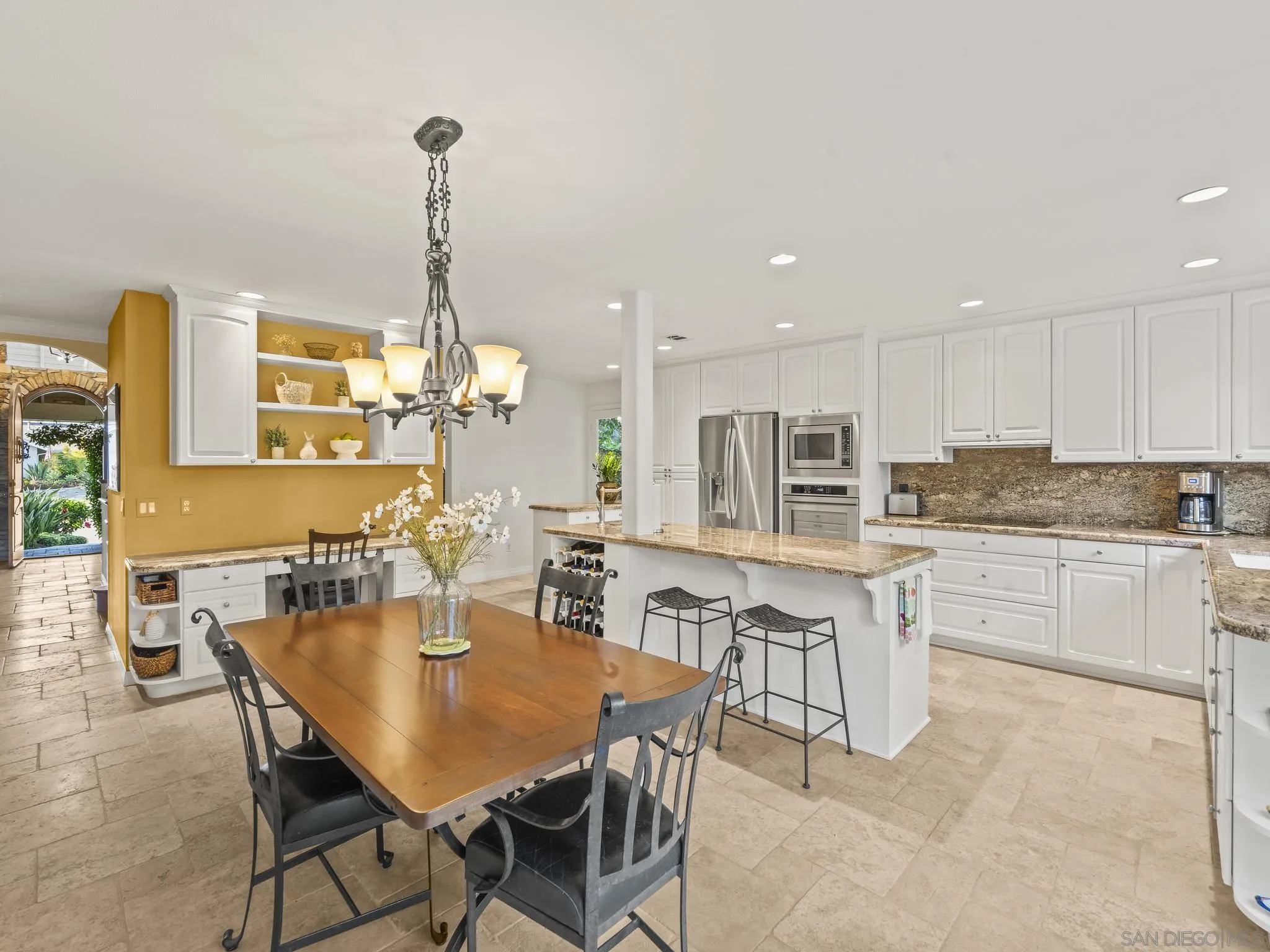 6502 La Paloma Street Carlsbad, CA 92009 - Photo 16 of 60 a kitchen with stainless steel appliances granite countertop a dining table chairs and white cabinets