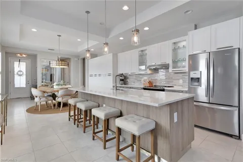 a kitchen with stainless steel appliances kitchen island granite countertop a table chairs and a refrigerator