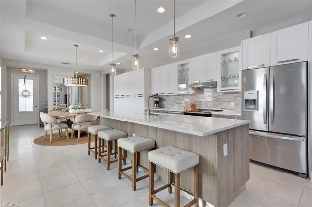 a kitchen with stainless steel appliances kitchen island granite countertop a table chairs and a refrigerator