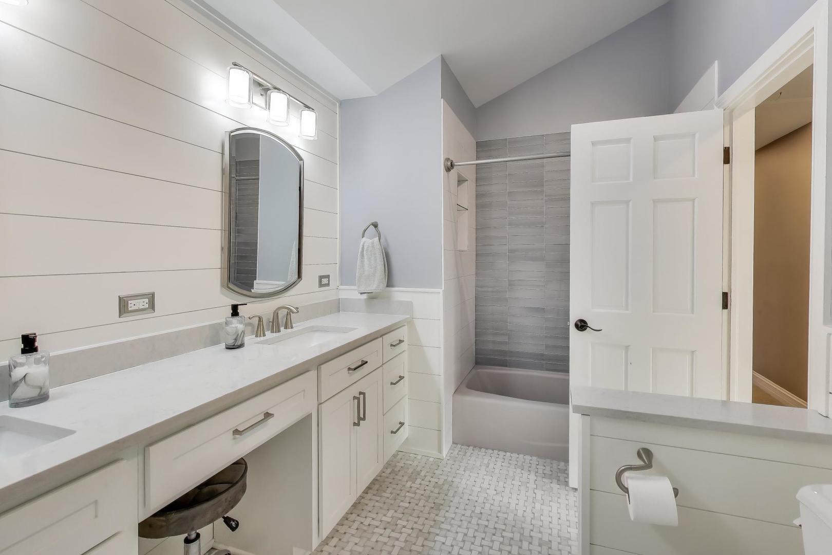 2103 Primrose Lane Naperville, IL 60565 - Photo 22 of 40 a bathroom with a double vanity sink a mirror and a bathtub