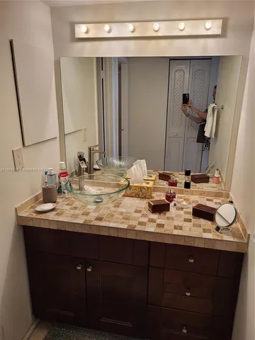 a bathroom with a granite countertop sink and a mirror