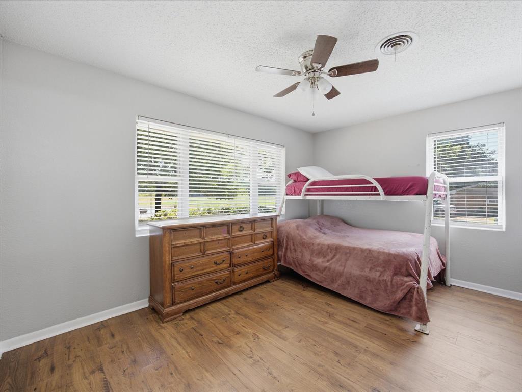 714 Decatur Street Bowie, TX 76230 - Photo 11 of 16 Bedroom number 2 with an Abundance of natural light, Ceiling Fan, vinyl plank flooring, and Baseboards