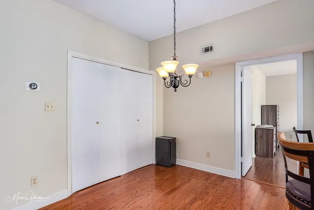 a view of an empty room with wooden floor and a chandelier