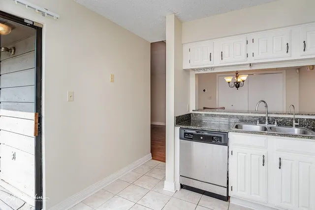 a kitchen with granite countertop white cabinets and stainless steel appliances
