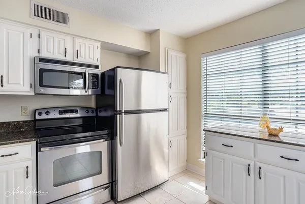 a kitchen with granite countertop cabinets stainless steel appliances and a window
