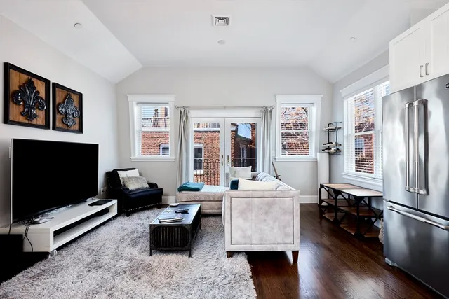 a living room with furniture flat screen tv and a refrigerator