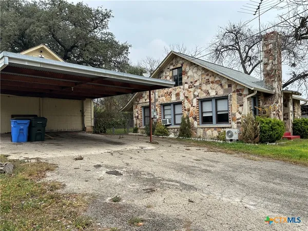 a backyard of a house with large trees and barbeque oven