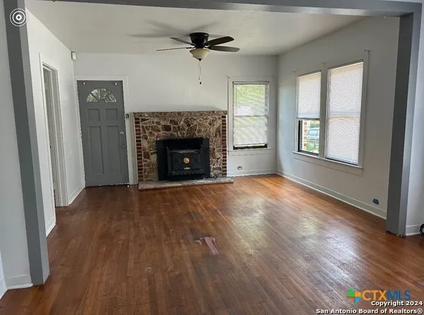 an empty room with wooden floor fireplace and windows