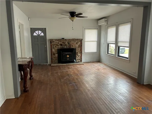 an empty room with windows fireplace and wooden floor