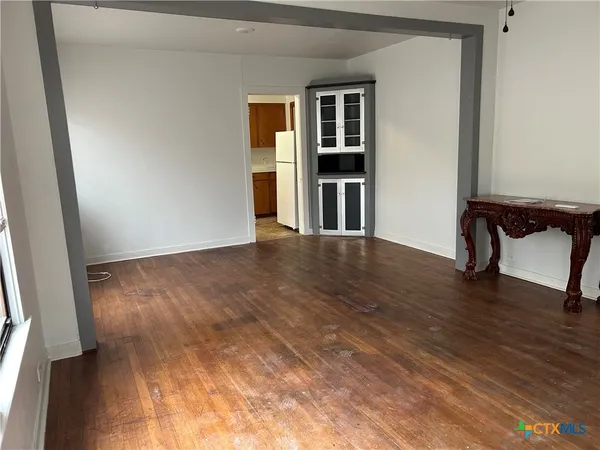 a view of an empty room with window and a kitchen
