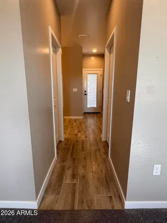 a view of a hallway with wooden floor and a bathroom