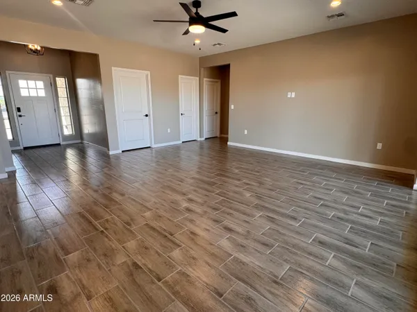 a view of an empty room with wooden floor and a window