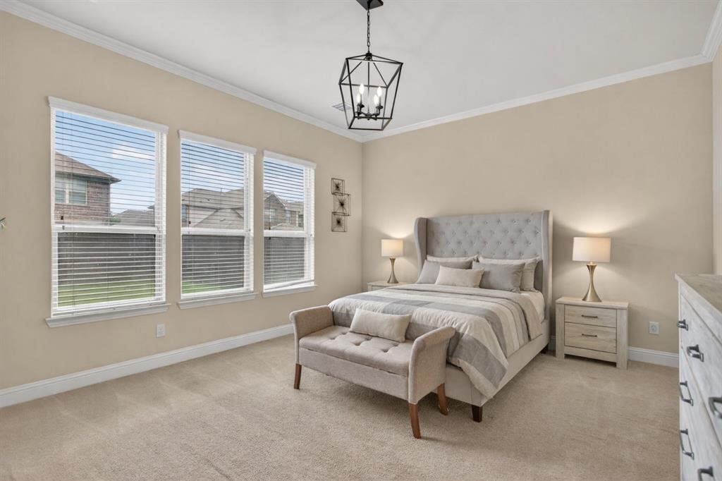 1022 Longhill Way Forney, TX 75126 - Photo 11 of 29 a spacious bedroom with a bed a chandelier and a window