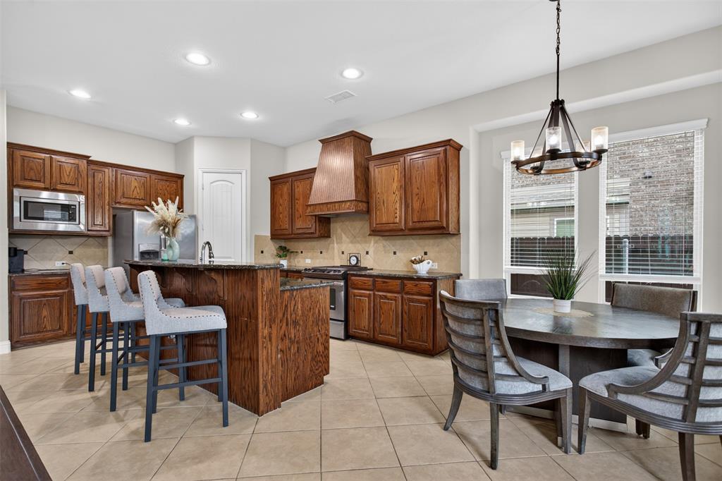 1022 Longhill Way Forney, TX 75126 - Photo 4 of 29 a kitchen with stainless steel appliances granite countertop a stove a refrigerator a kitchen island a dining table and chairs