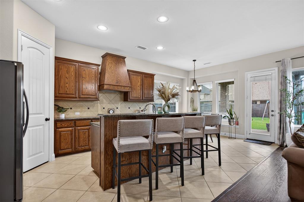 1022 Longhill Way Forney, TX 75126 - Photo 5 of 29 a kitchen with kitchen island granite countertop wooden cabinets and stainless steel appliances