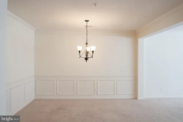 a view of an empty room with chandelier fan