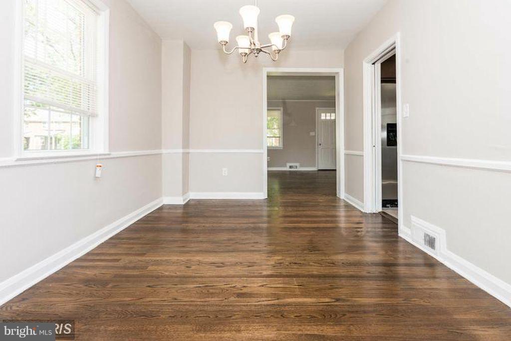 1239 Cedarcroft Road Baltimore, MD 21239 - Photo 5 of 16 a view of an empty room with wooden floor and a window