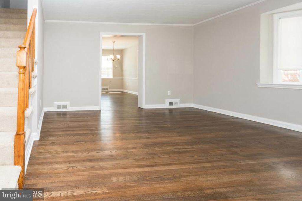 1239 Cedarcroft Road Baltimore, MD 21239 - Photo 6 of 16 a view of an empty room with wooden floor and a window