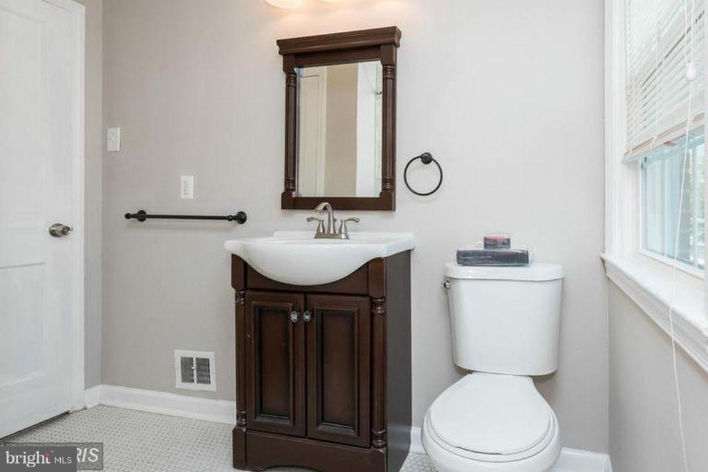 1239 Cedarcroft Road Baltimore, MD 21239 - Photo 8 of 16 a bathroom with a toilet a sink and mirror